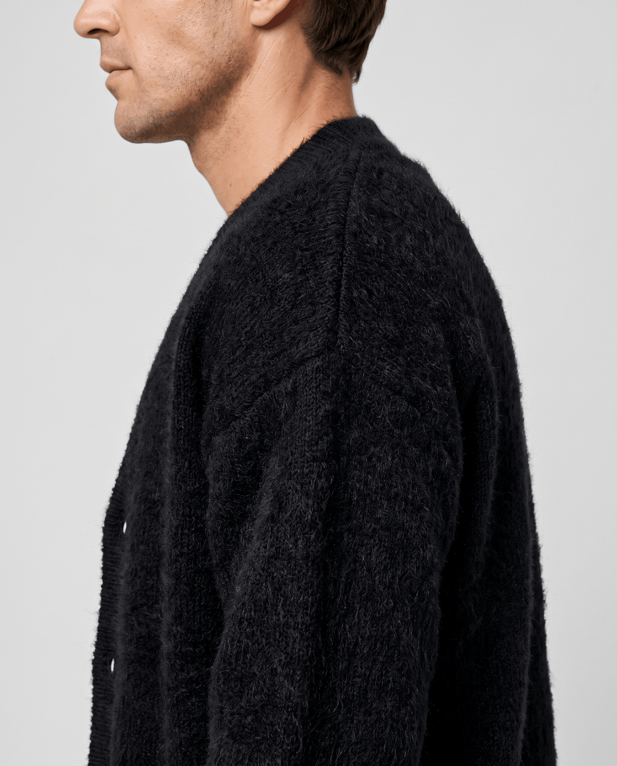 Side profile of the black cardigan showing the long-pile knit across the shoulder