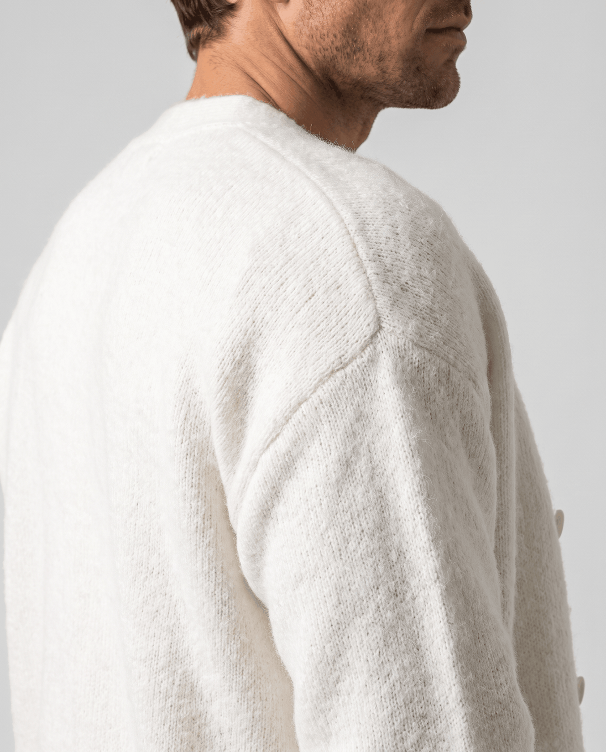Shoulder detail of the white cardigan showing the soft knit and dropped seam