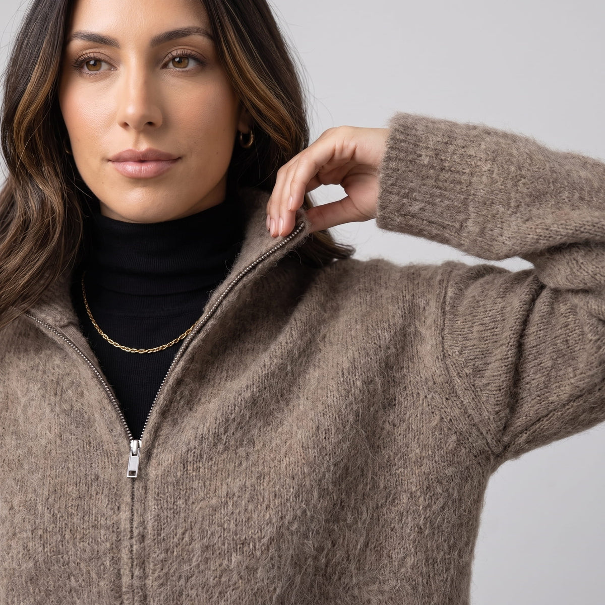 Model in the taupe brushed knit cardigan with a black turtleneck and gold chain necklace