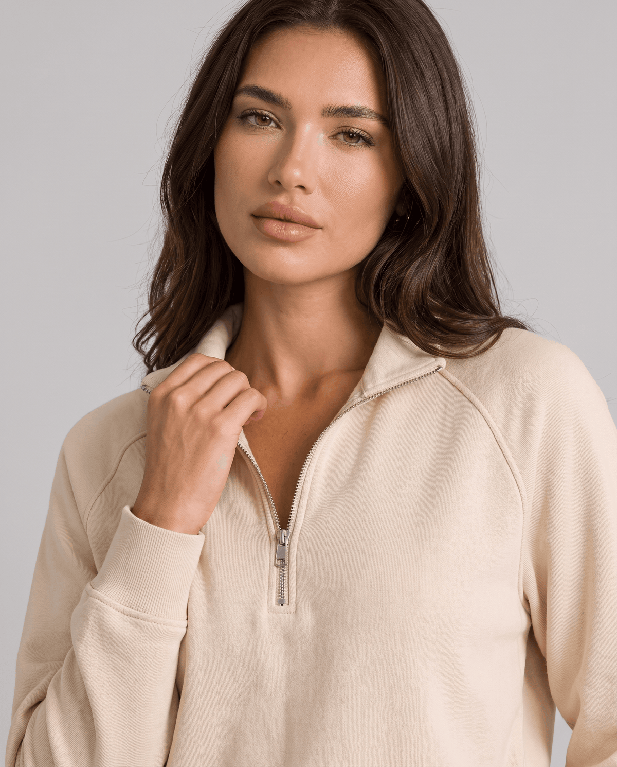 Close-up of beige half-zip collar and ribbed cuff on a model