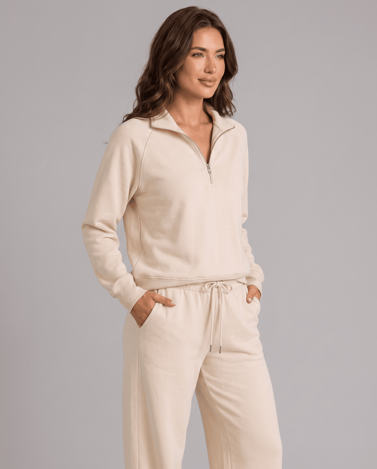 Woman in beige half-zip top and matching pants, three-quarter front view