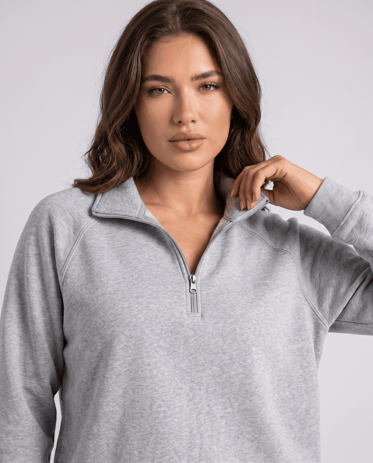 Close-up of gray half-zip collar and raglan sleeve on a model touching the collar