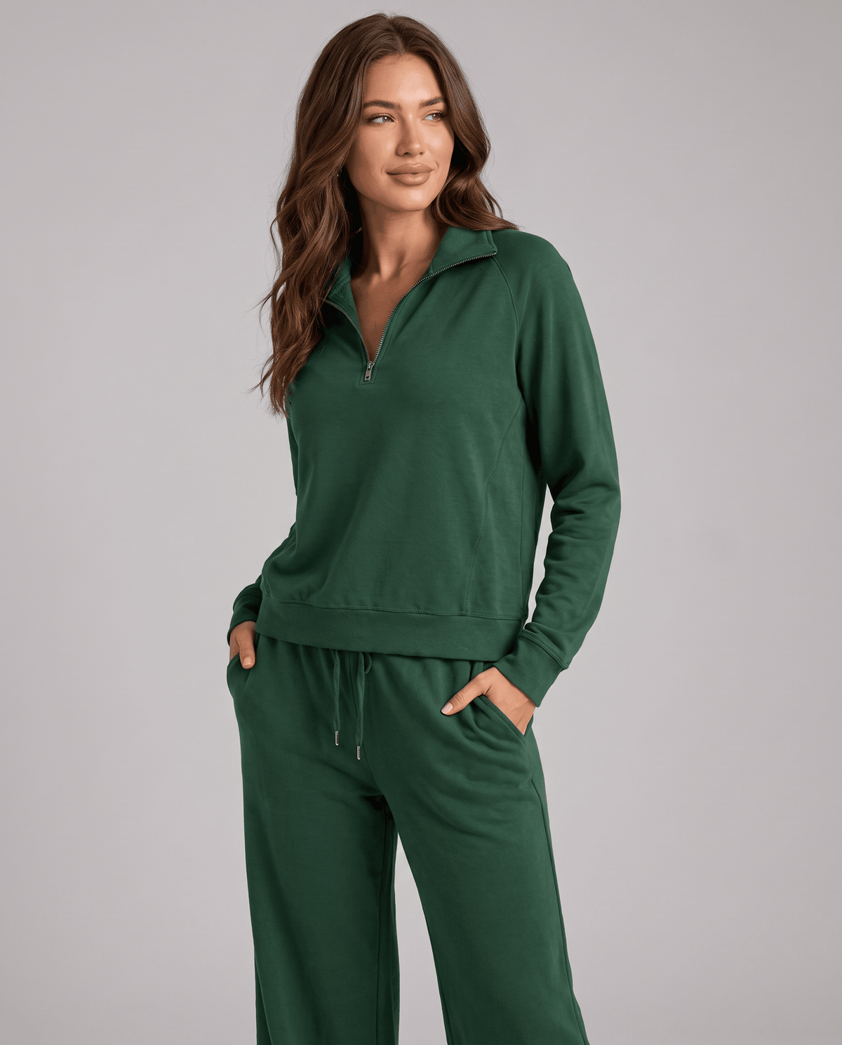 Woman in green half-zip top and wide-leg pants with one hand in the pocket