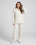 Woman wearing a beige ribbed knit half-zip loungewear set with a folded collar and wide-leg pants, front view