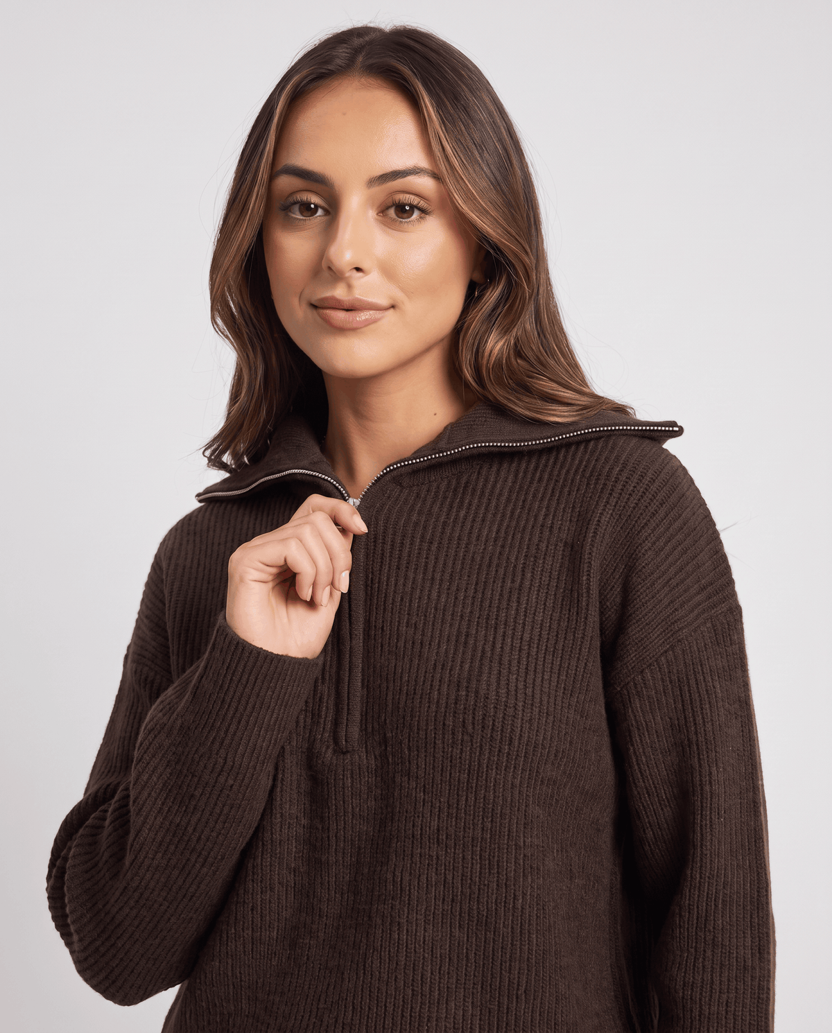 Woman holding the half-zip pull on the dark brown ribbed knit pullover, close-up