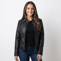 Woman wearing a black faux leather jacket with a round neckline, zip-front closure, and fitted silhouette over a black knit top and blue jeans.