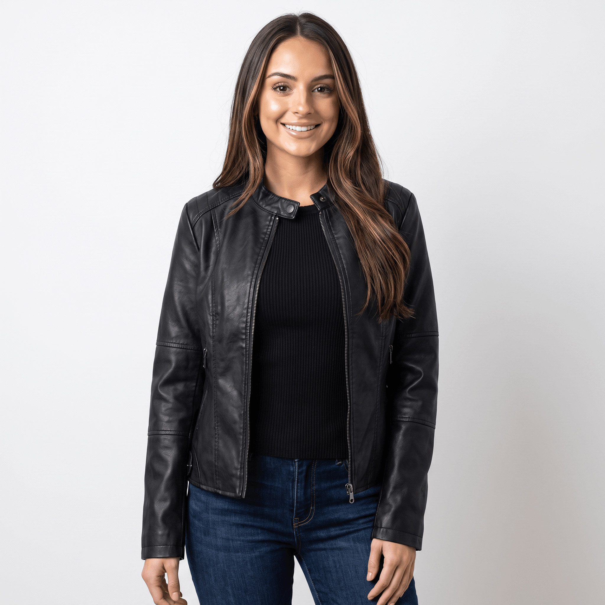 Woman wearing a black faux leather jacket with a round neckline, zip-front closure, and fitted silhouette over a black knit top and blue jeans.