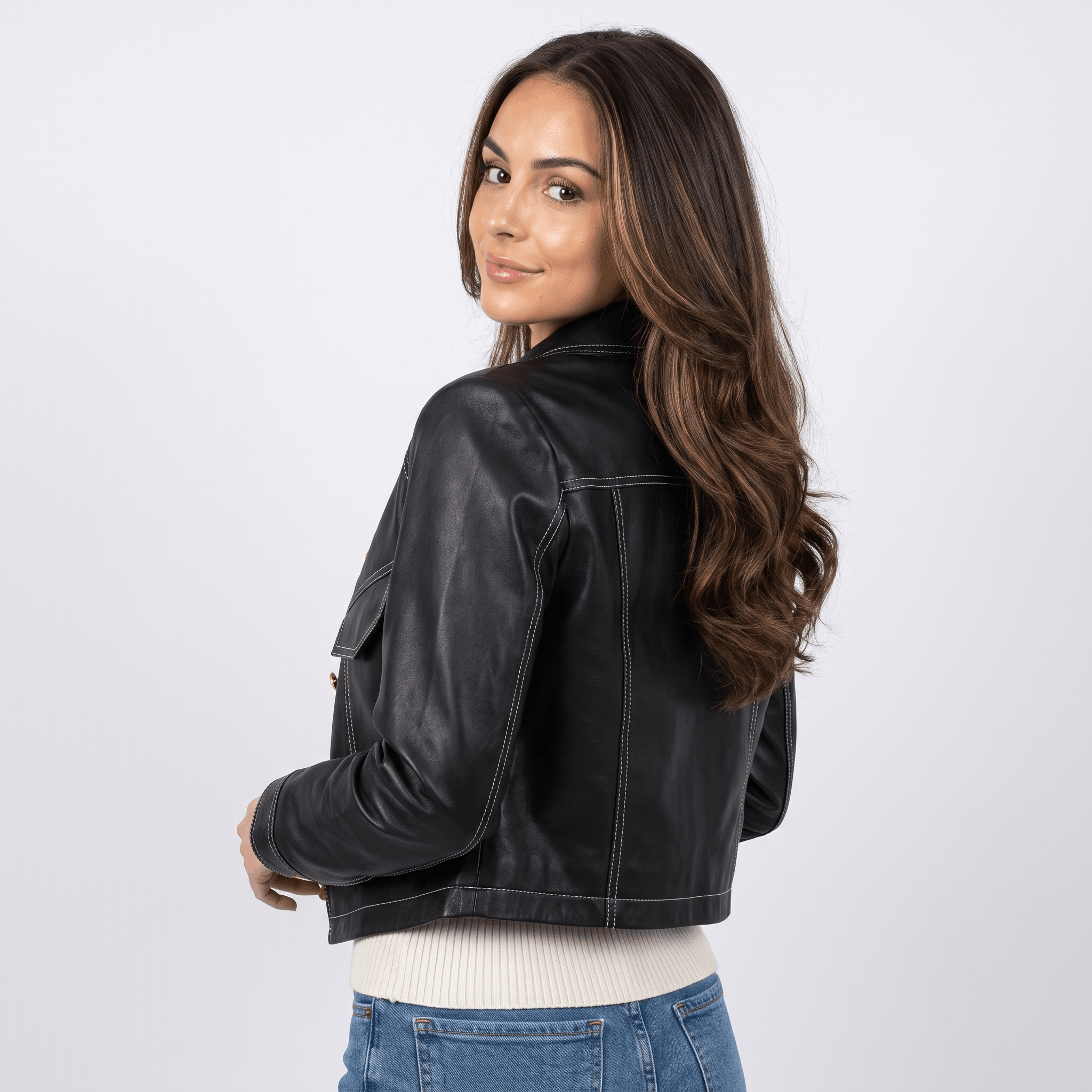 Back view of a women's black faux leather jacket with a cropped silhouette, long sleeves, and structured design.