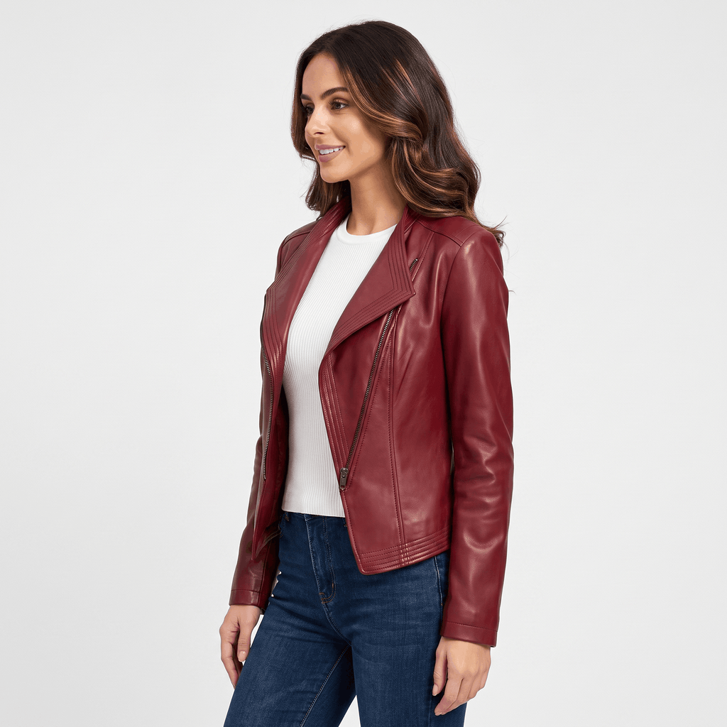 Three-quarter view of a woman wearing a burgundy leather moto jacket featuring a fitted design, asymmetrical zipper, and notched lapel.
