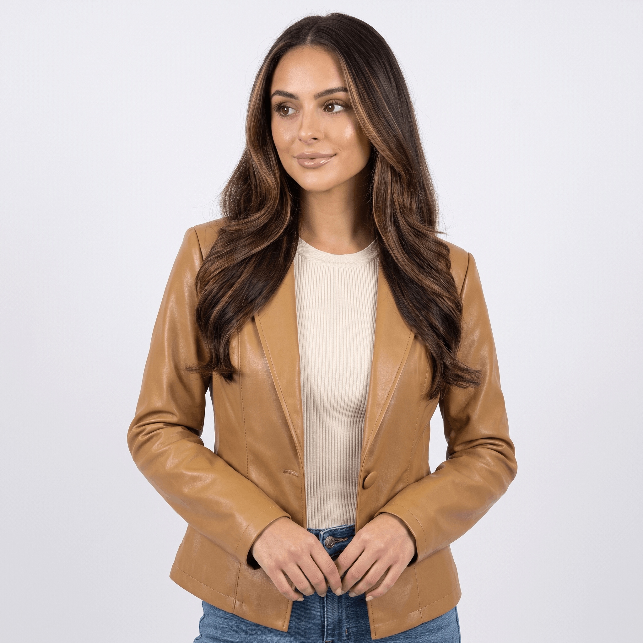 Woman wearing a camel faux leather blazer with a notched lapel, single-button closure, and tailored fit over a beige top.