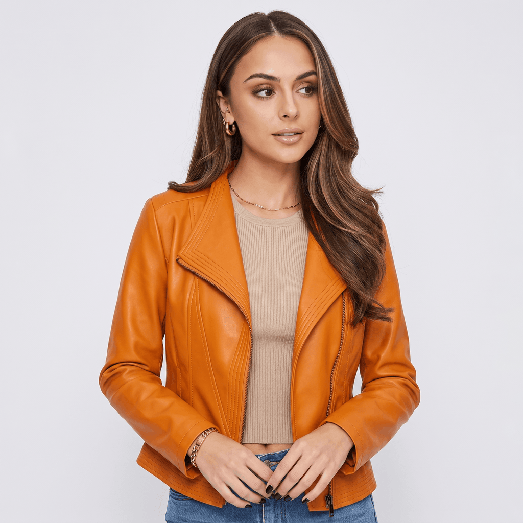 Woman wearing an orange leather moto jacket with an asymmetrical zip closure, notched lapel, and fitted silhouette.