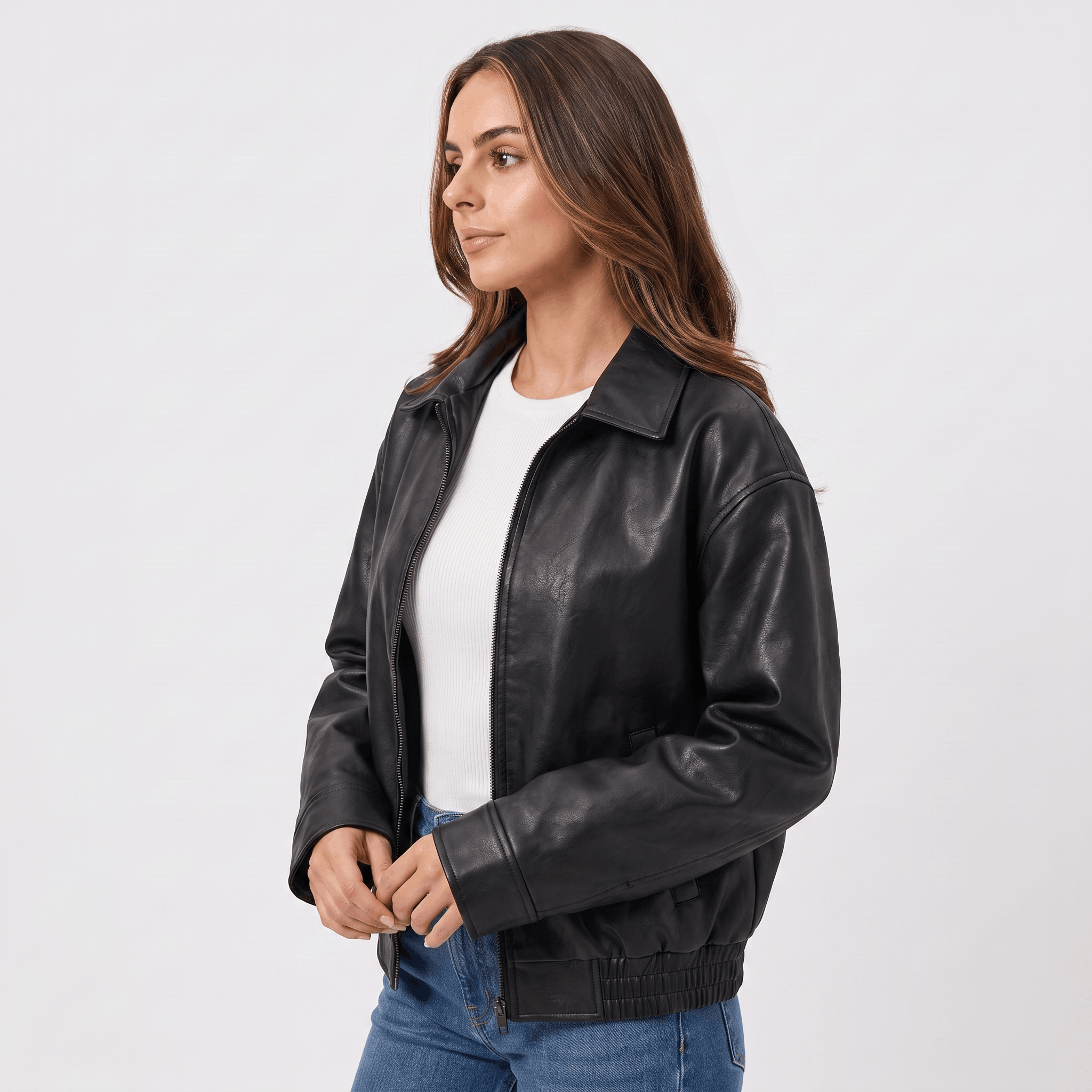 Side view of a woman wearing a black faux leather jacket featuring a straight-fit silhouette, zip-front closure, and classic collar.