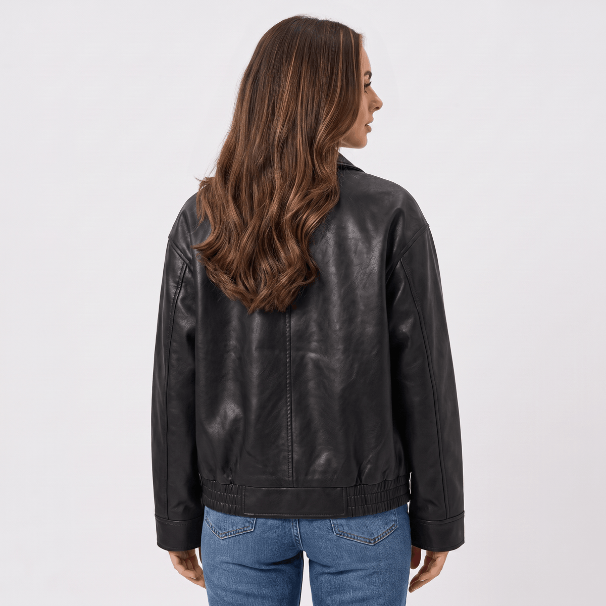 Back view of a women's black faux leather jacket with a smooth faux leather finish, long sleeves, and relaxed fit.