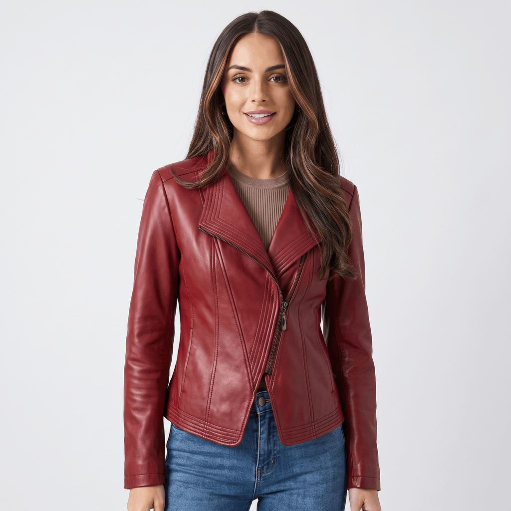 Woman wearing a burgundy leather moto jacket featuring an asymmetrical zipper, notched lapel, fitted design, and blue jeans.