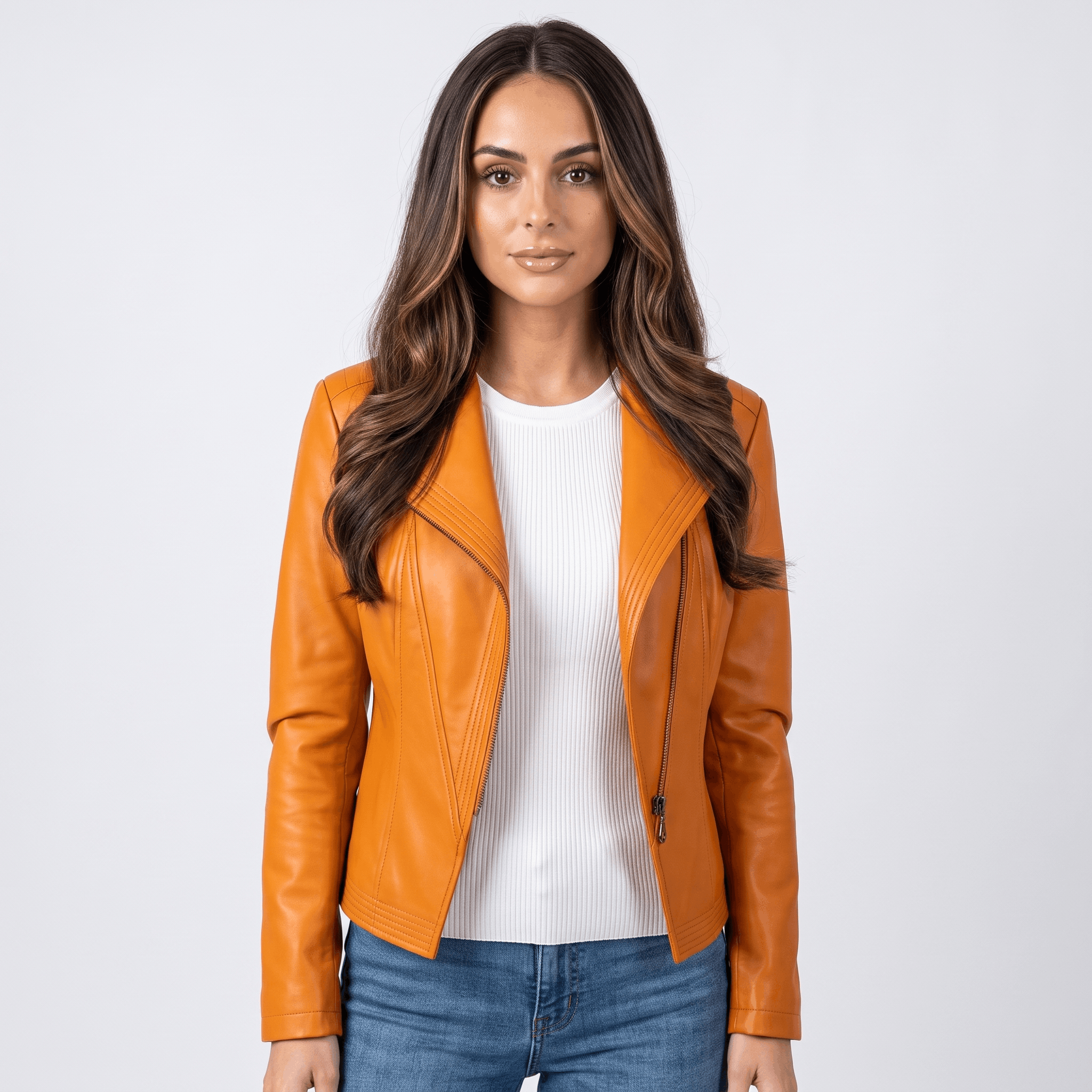 Woman wearing an orange leather moto jacket with an asymmetrical zip closure, notched lapel, fitted silhouette, and blue jeans.