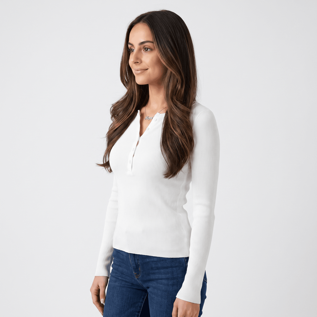 Side view of a woman wearing a white ribbed henley top with a fitted silhouette, long sleeves, and buttoned neckline.