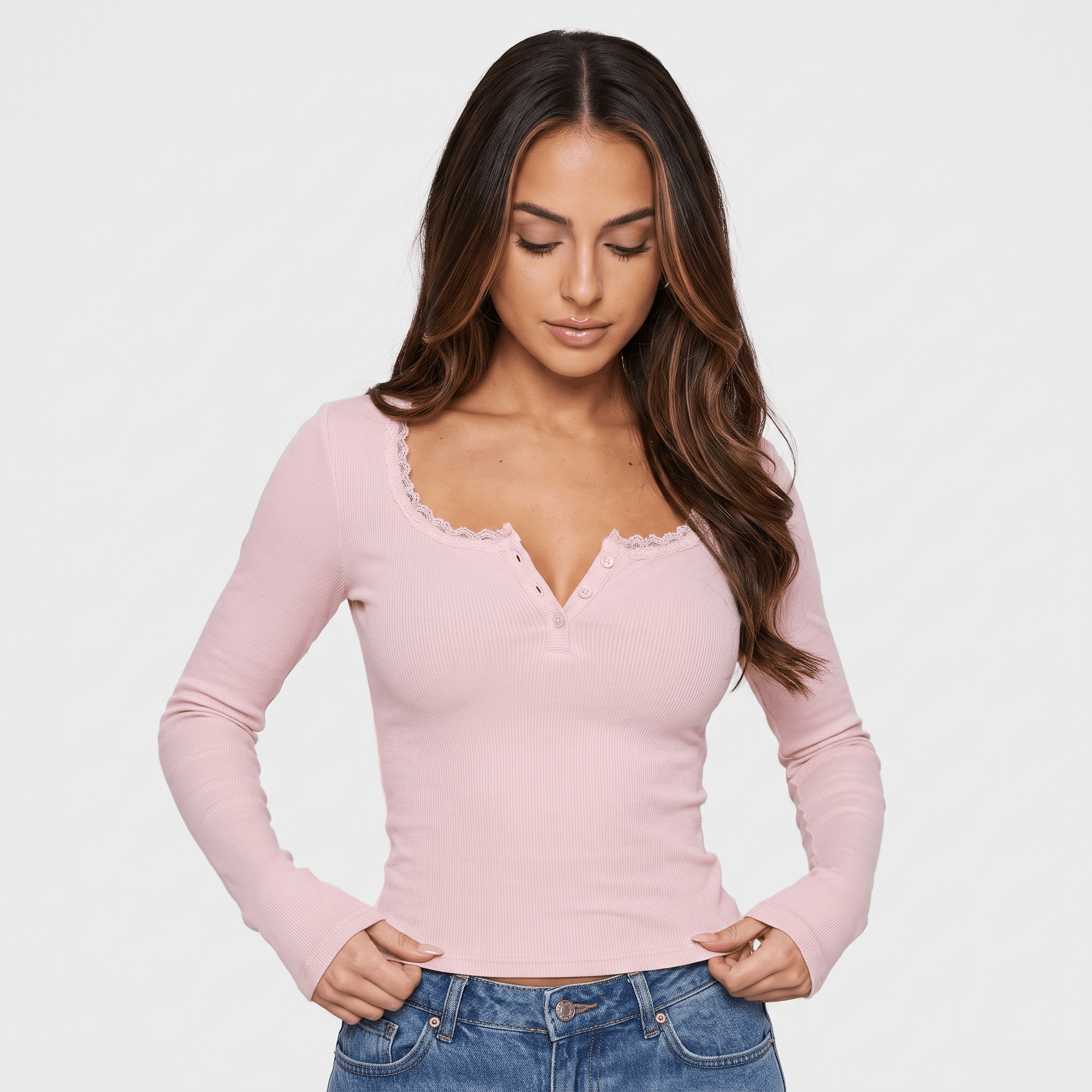 Woman wearing a pink ribbed long sleeve top with a scalloped neckline, button front, fitted silhouette, and blue jeans.