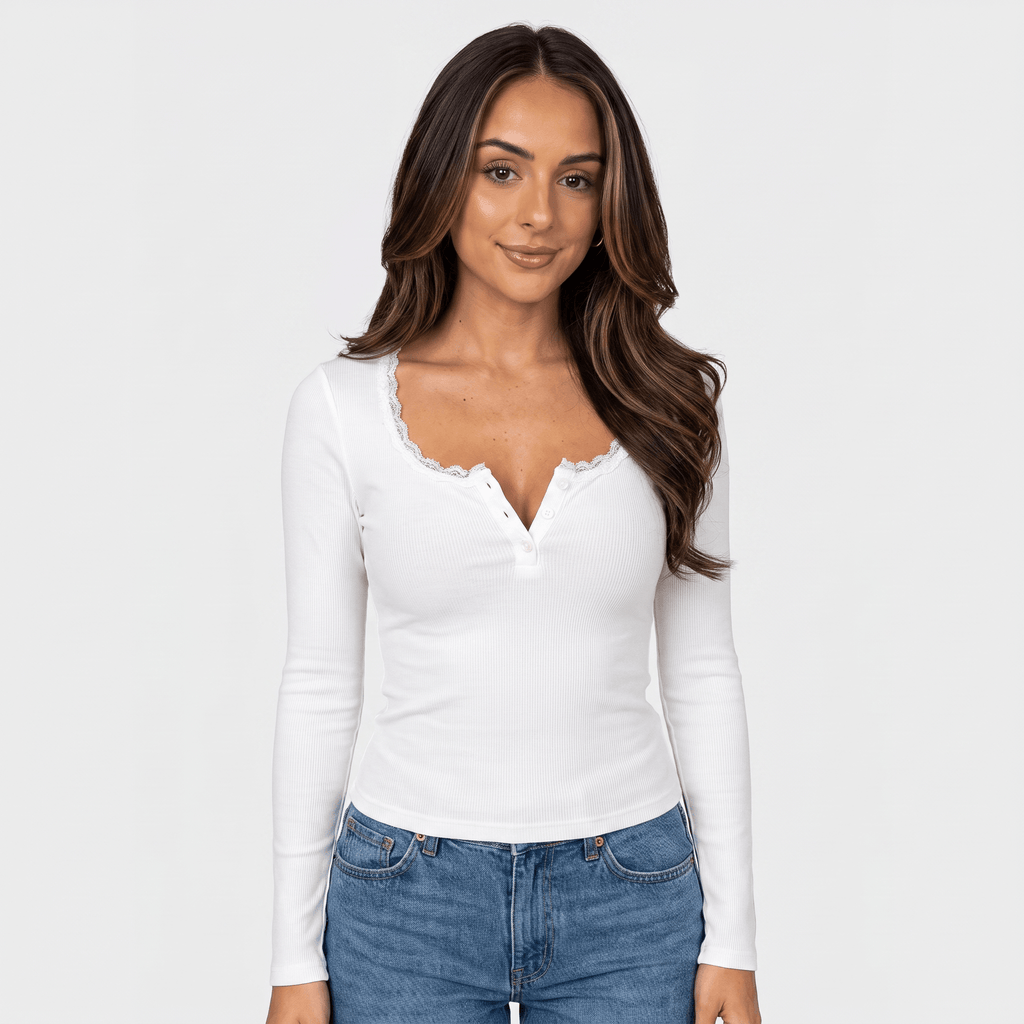 Woman wearing a white ribbed long sleeve top with a scalloped neckline, button front, fitted silhouette, and blue jeans.