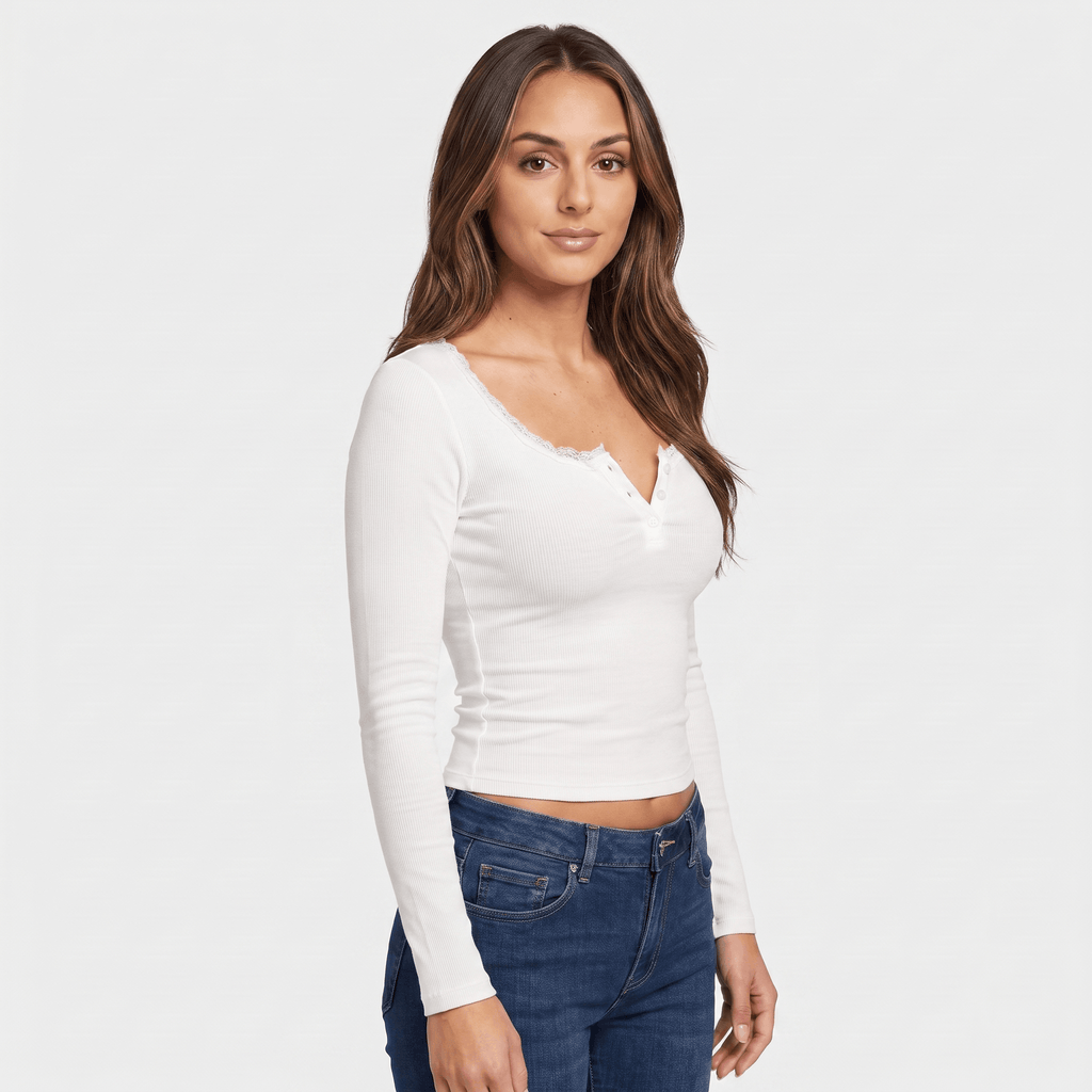 Three-quarter view of a woman wearing a white fitted ribbed top with a scalloped neckline, button front, and long sleeves.