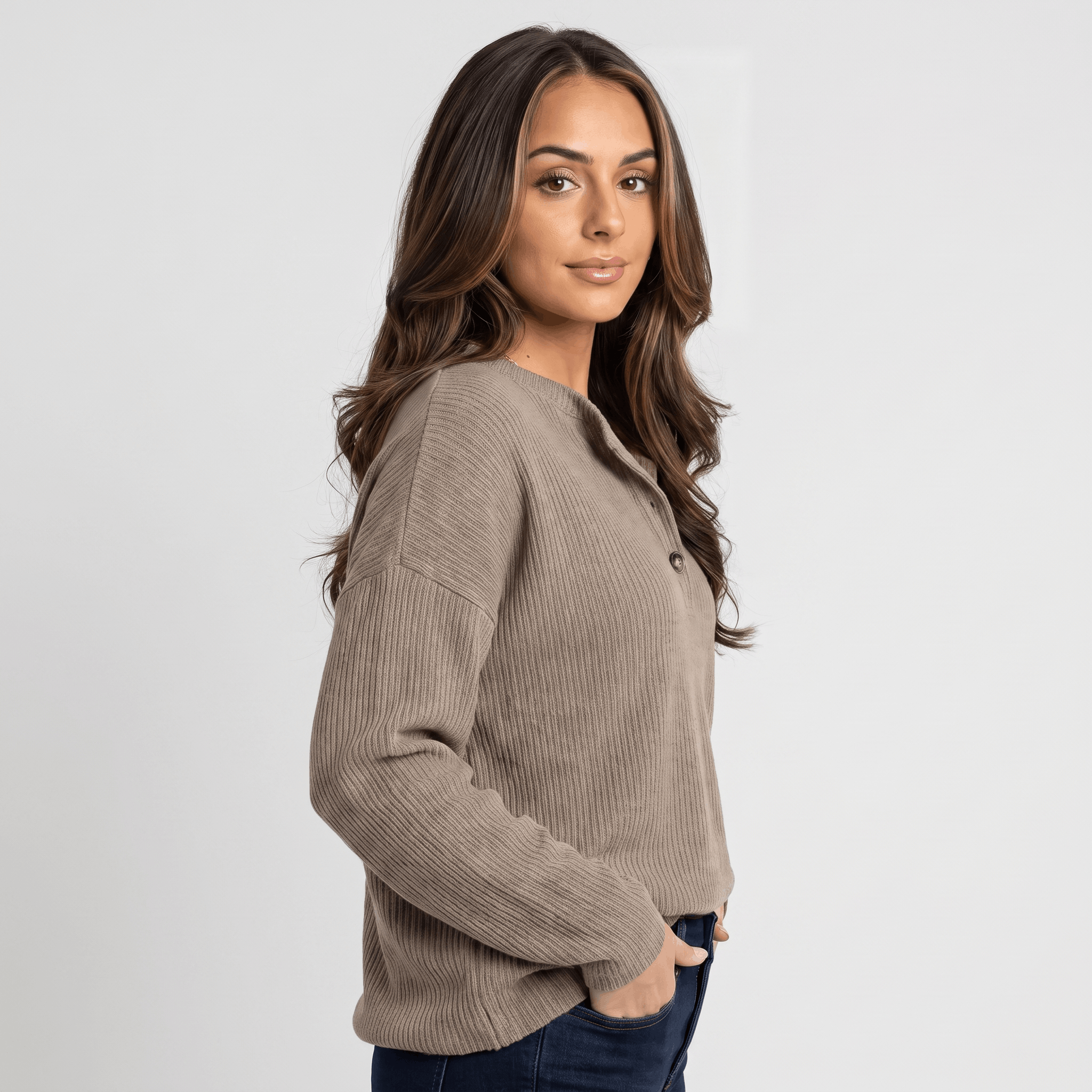 Side view of a woman wearing a taupe ribbed henley sweater with a button neckline and long sleeves.