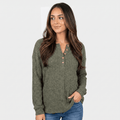 Woman wearing an olive green textured henley sweater with a button neckline, long sleeves, and relaxed fit with blue jeans.