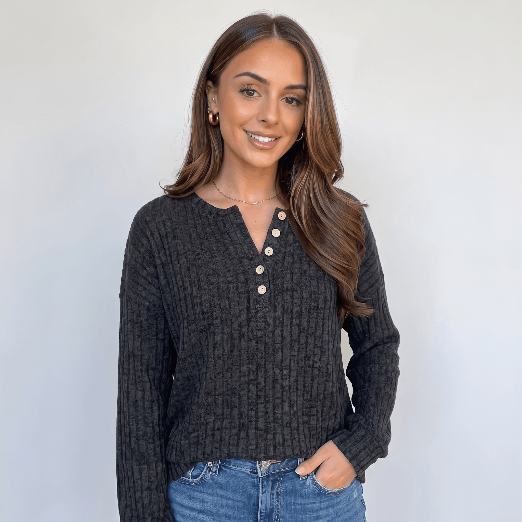 Woman wearing a black  textured henley sweater with a button neckline, long sleeves, and relaxed fit.