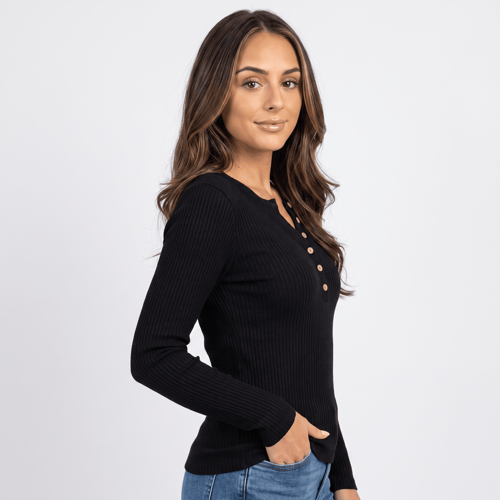 Woman wearing a black textured henley sweater with a button neckline and long sleeves.