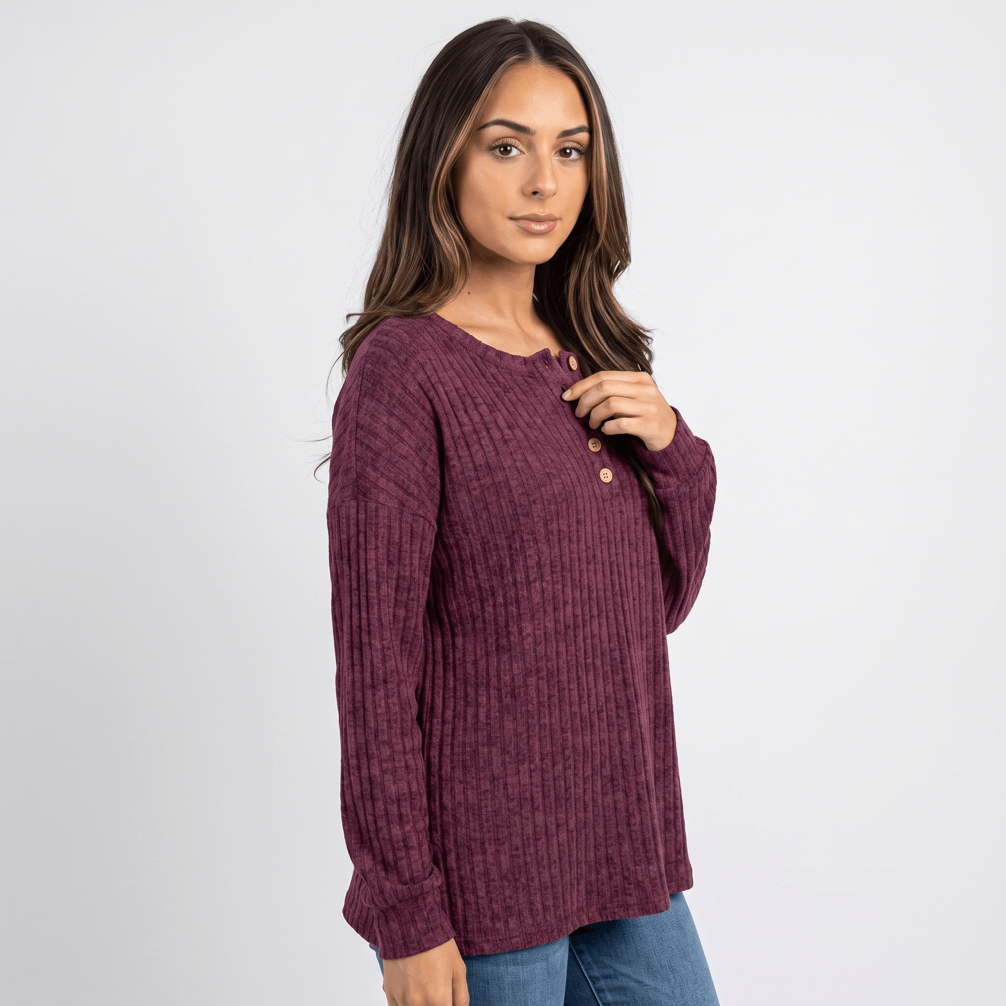 Side view of a woman wearing a burgundy textured henley sweater with a button neckline and long sleeves.