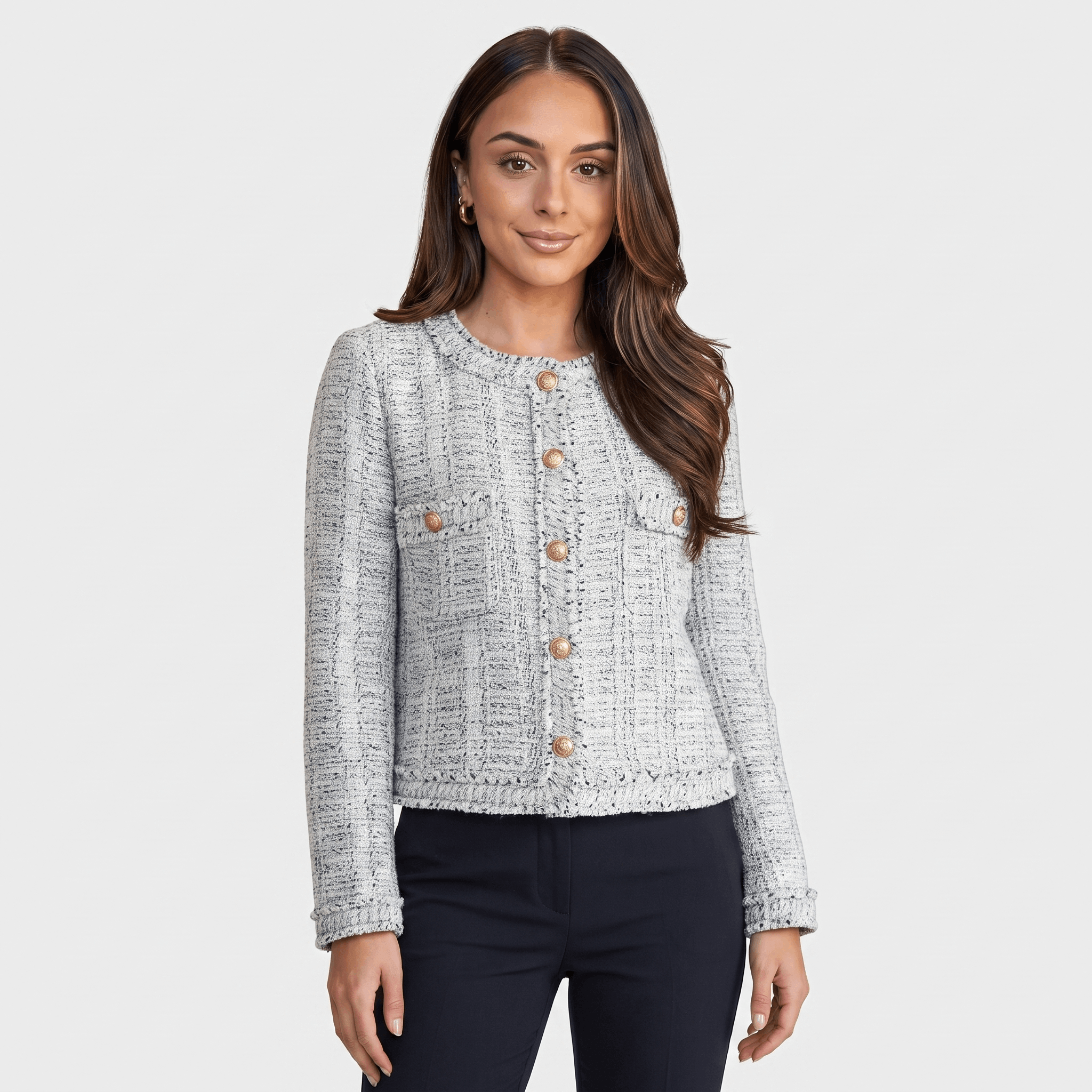 Woman wearing a light gray textured tweed jacket with gold-tone buttons, round neckline, long sleeves, and tailored cropped silhouette, paired with dark trousers.