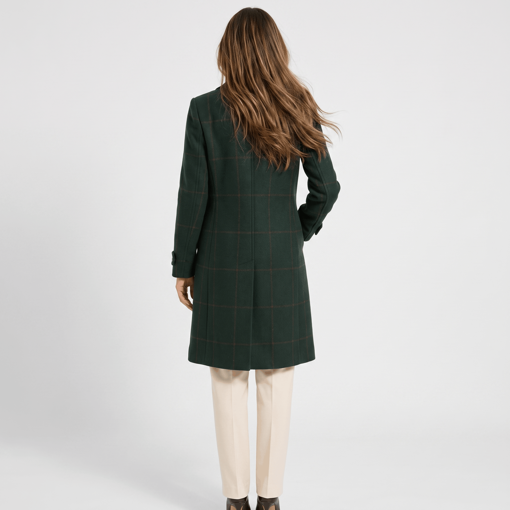 Back view of a woman wearing a dark green tailored long coat with long sleeves and a structured silhouette.
