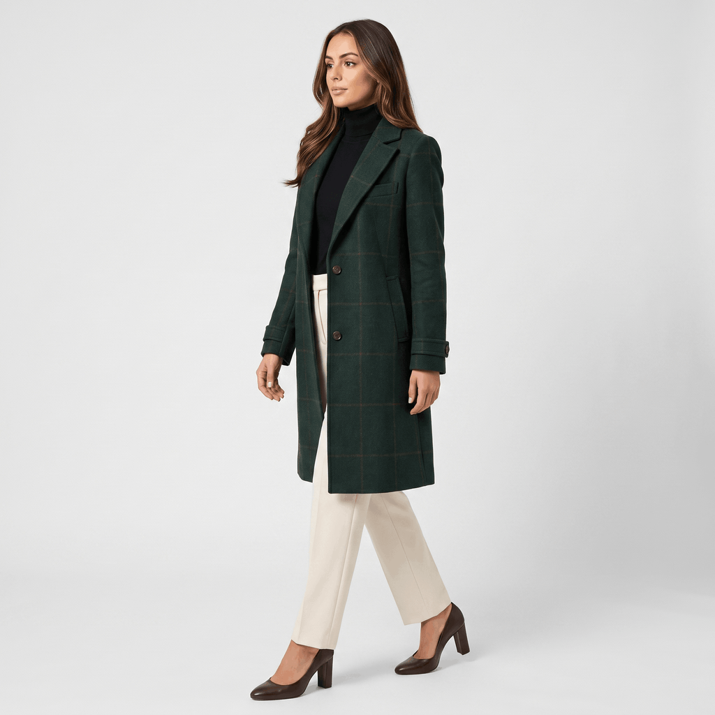 Side view of a woman wearing a dark green tailored long coat with a structured silhouette and long sleeves.