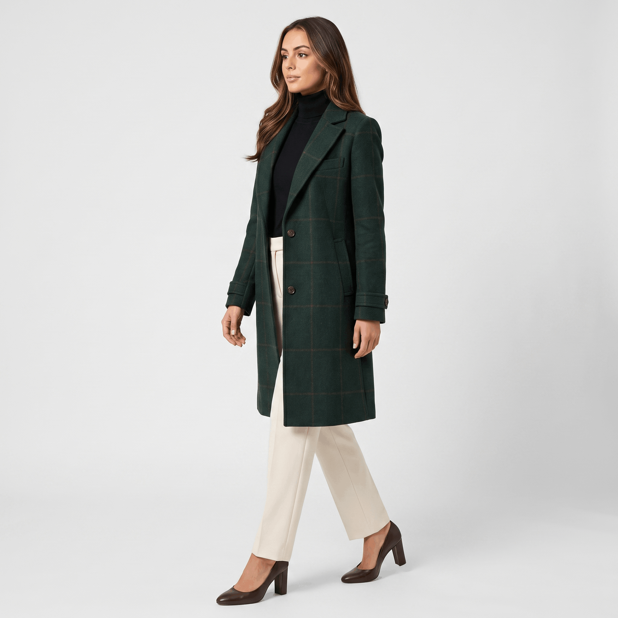 Side view of a woman wearing a dark green tailored long coat with a structured silhouette and long sleeves.