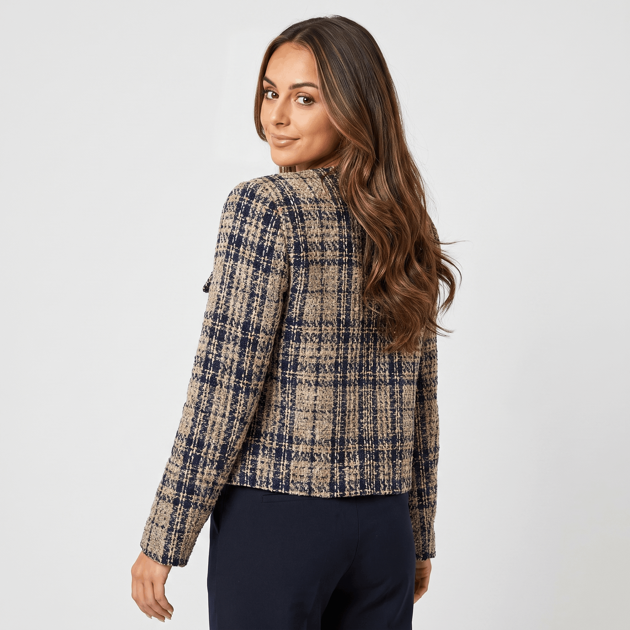 Back view of a woman wearing a blue and beige plaid tweed jacket with a fitted silhouette and long sleeves.