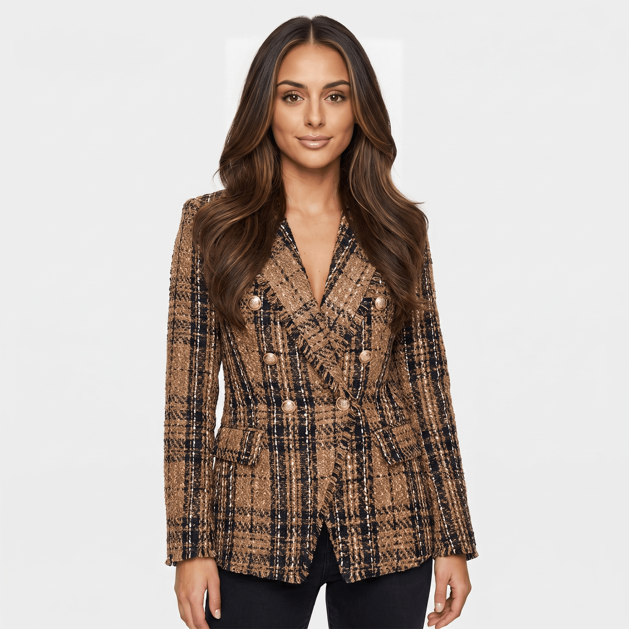 Woman wearing a brown plaid tweed blazer with a double-breasted button closure, notched lapels, long sleeves, and tailored fit paired with black trousers.