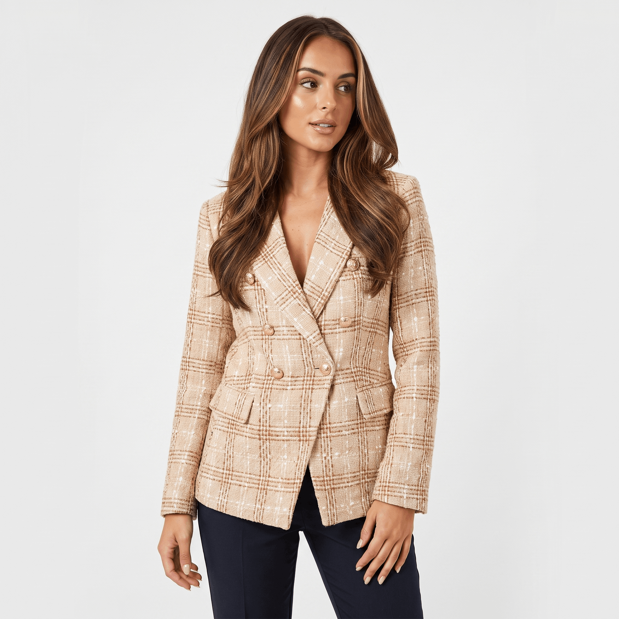 Woman wearing a beige plaid tweed blazer with gold-tone buttons, notched lapels, and tailored fit over a light top and dark trousers.