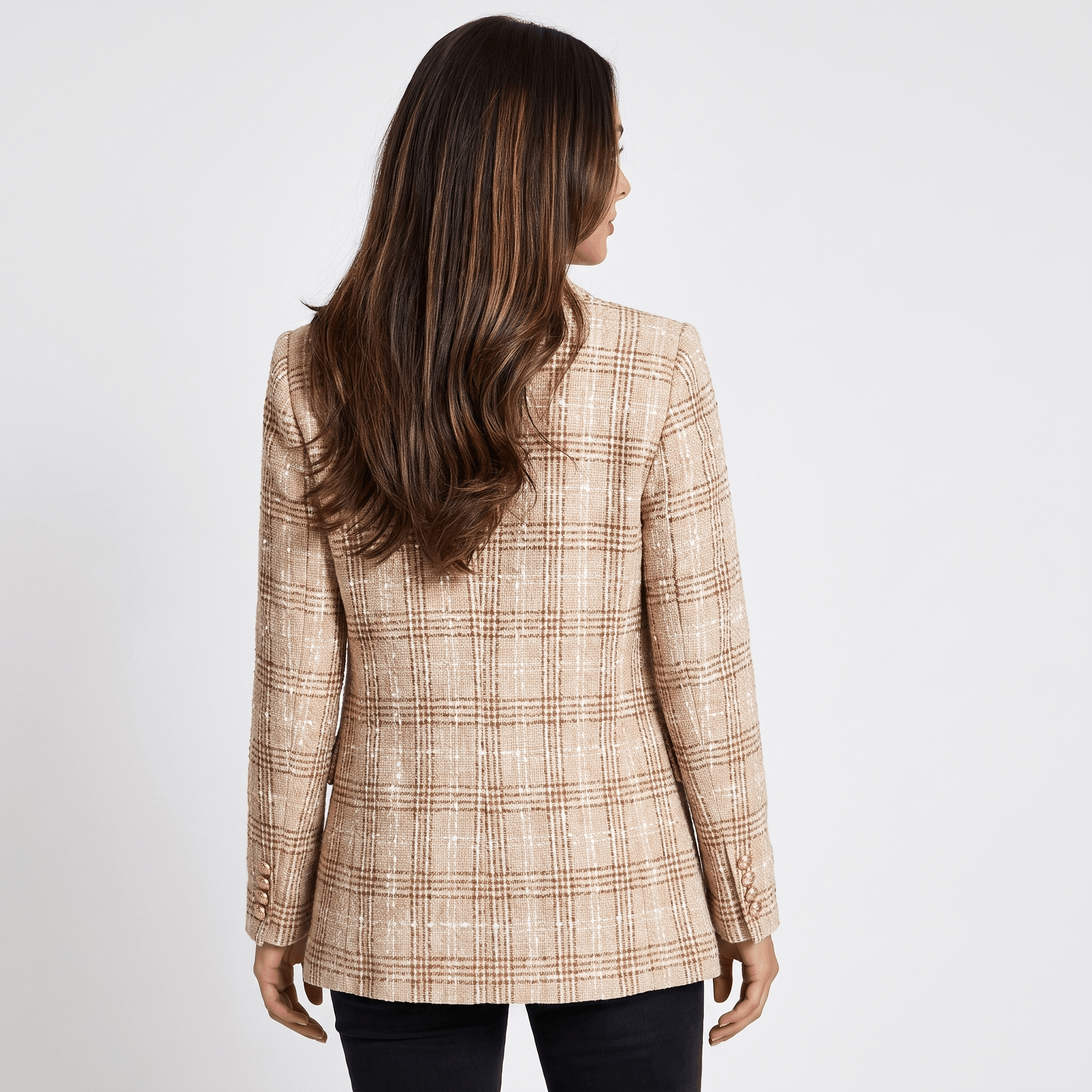 Woman wearing a red plaid tweed blazer with gold-tone buttons, notched lapels, and tailored fit over a black top and dark trousers.