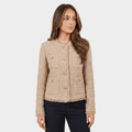 Woman wearing a beige textured tweed jacket with gold-tone buttons, round neckline, long sleeves, and cropped tailored silhouette paired with dark trousers.