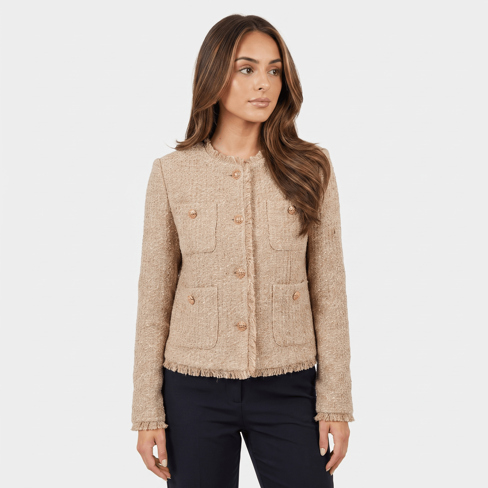 Woman wearing a beige textured tweed jacket with gold-tone buttons, round neckline, long sleeves, and cropped tailored silhouette paired with dark trousers.