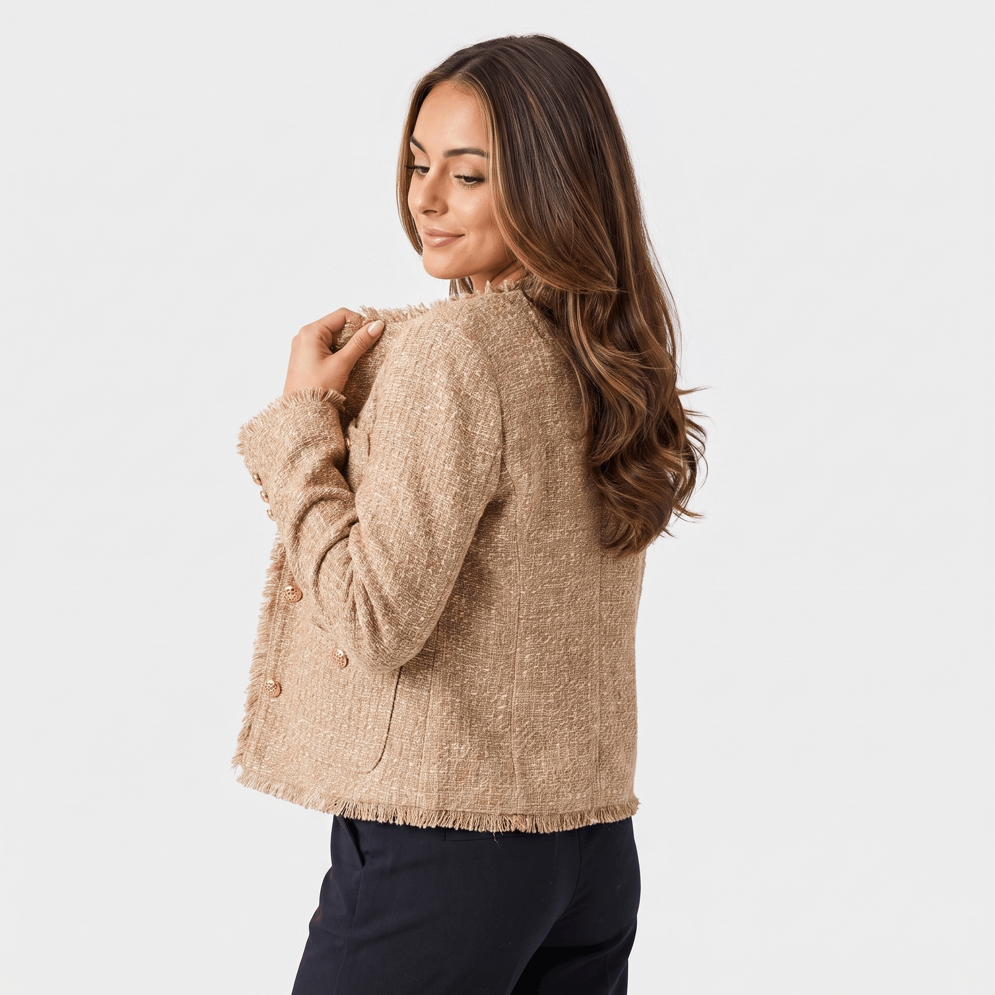Back view of a woman wearing a beige textured tweed jacket with a cropped tailored fit and long sleeves.