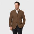 Man wearing a brown textured blazer with a notched lapel, button-front closure, flap pockets, and tailored fit over a white dress shirt and black trousers.