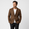 Man wearing a brown textured blazer with notched lapels, button closure, flap pockets, and tailored fit over a white crew-neck shirt and black trousers.