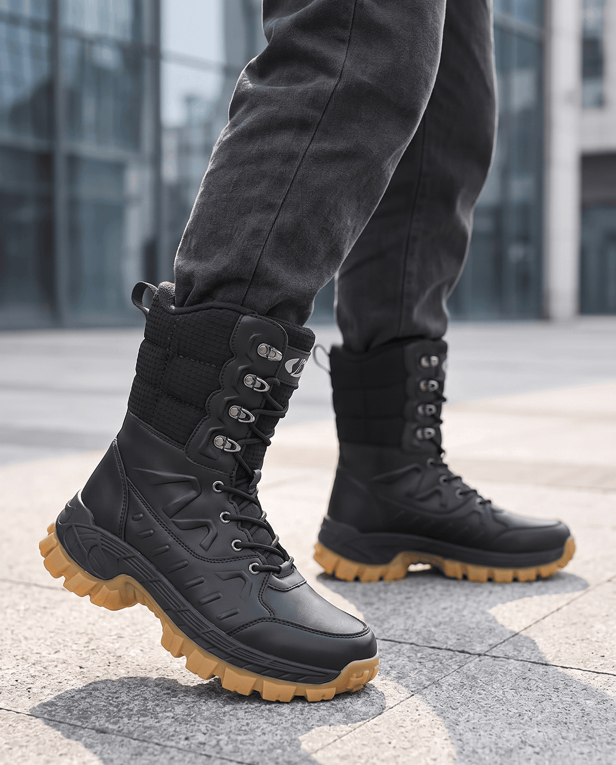 Man wearing black lace-up boots with dark jeans on a city sidewalk