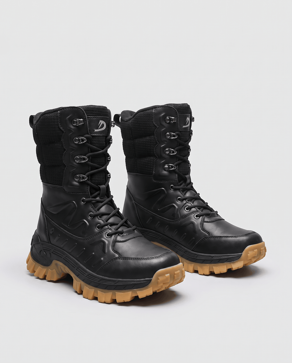 Pair of black boots angled to show cord laces and chunky tan soles