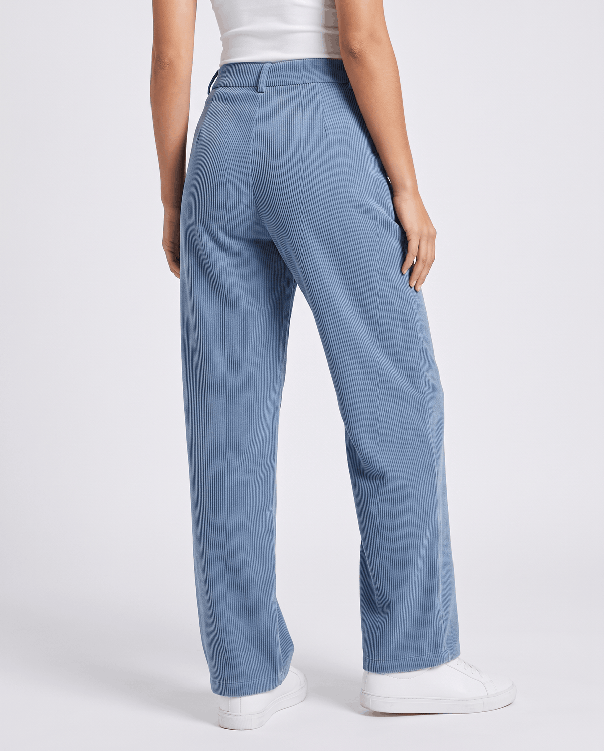 Back view of pale blue wide-leg trousers with belt loops, worn with white sneakers