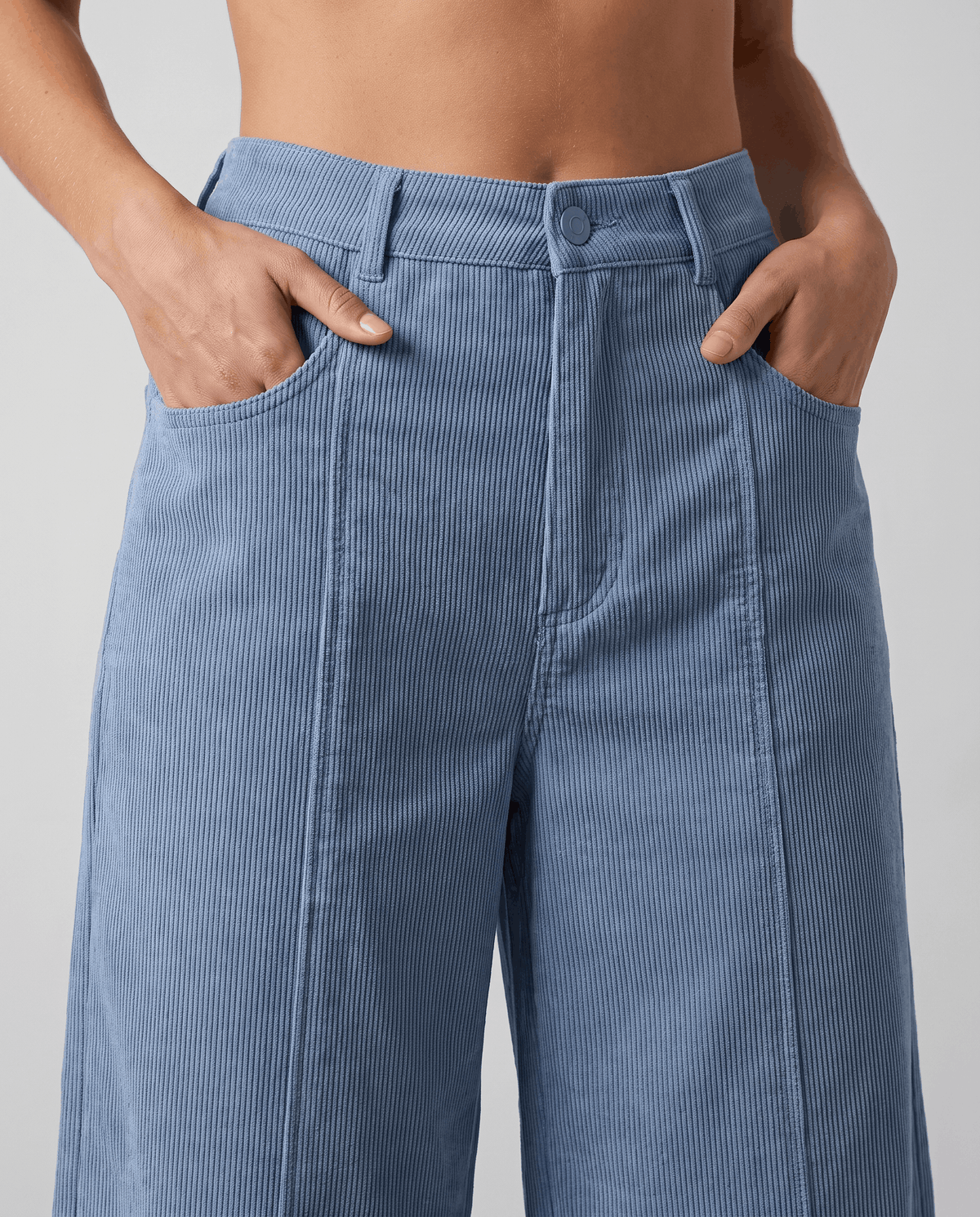 Close-up of the high button waist with belt loops and hands resting in front pockets