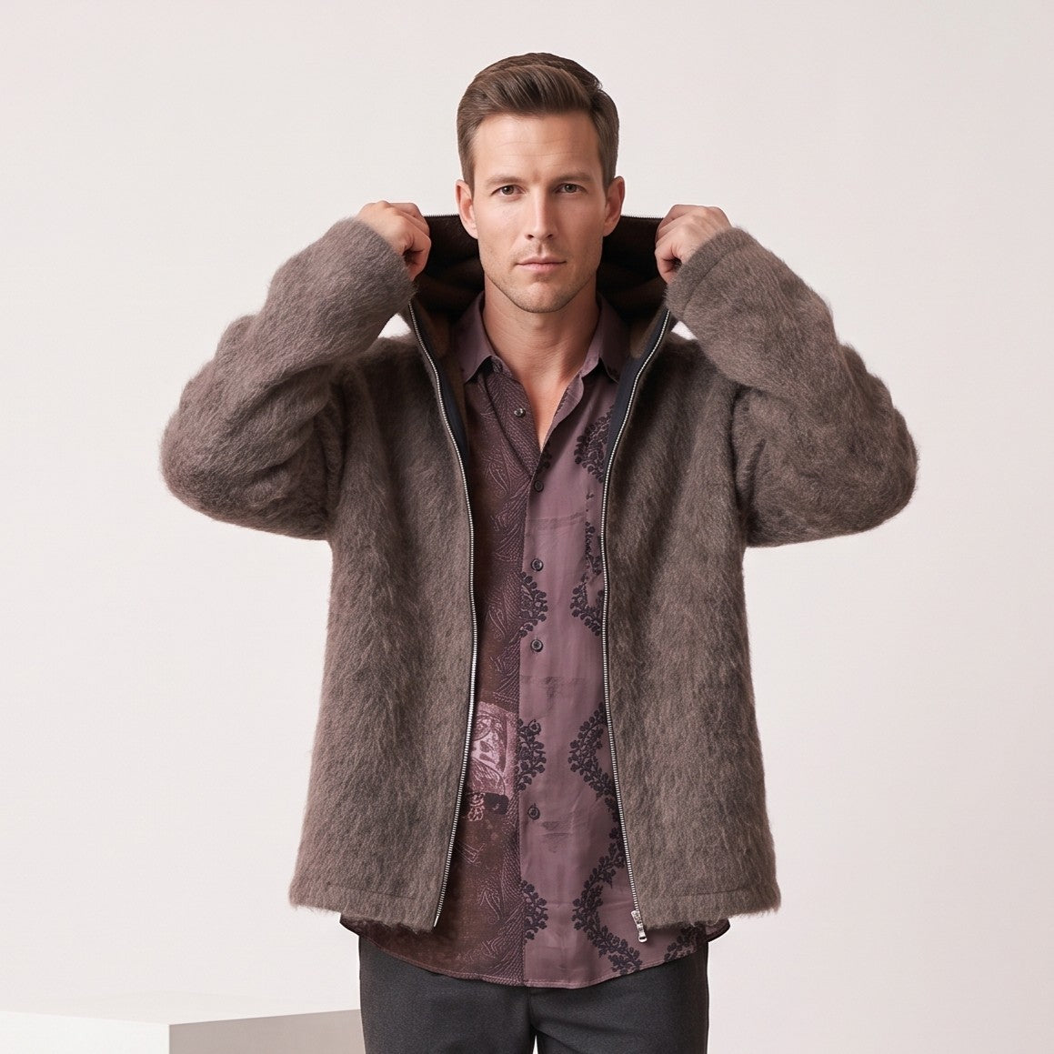 Brown hooded cardigan over a burgundy shirt with hands adjusting the hood