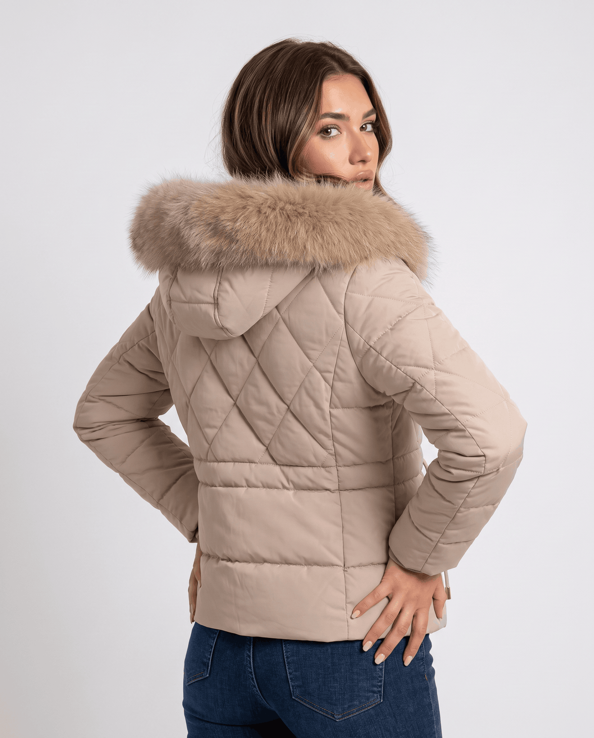 Back view of beige quilted jacket with plush hood trim, worn with jeans