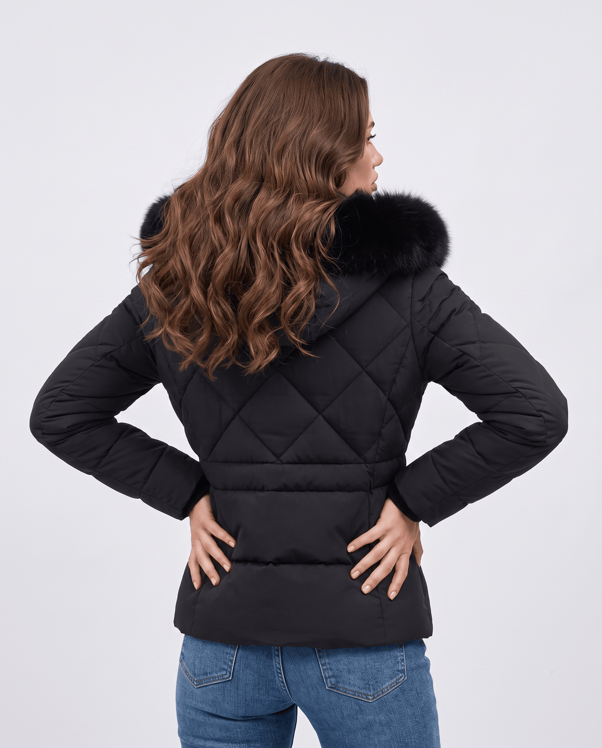 Back view of black quilted jacket with plush-trim hood and long wavy hair