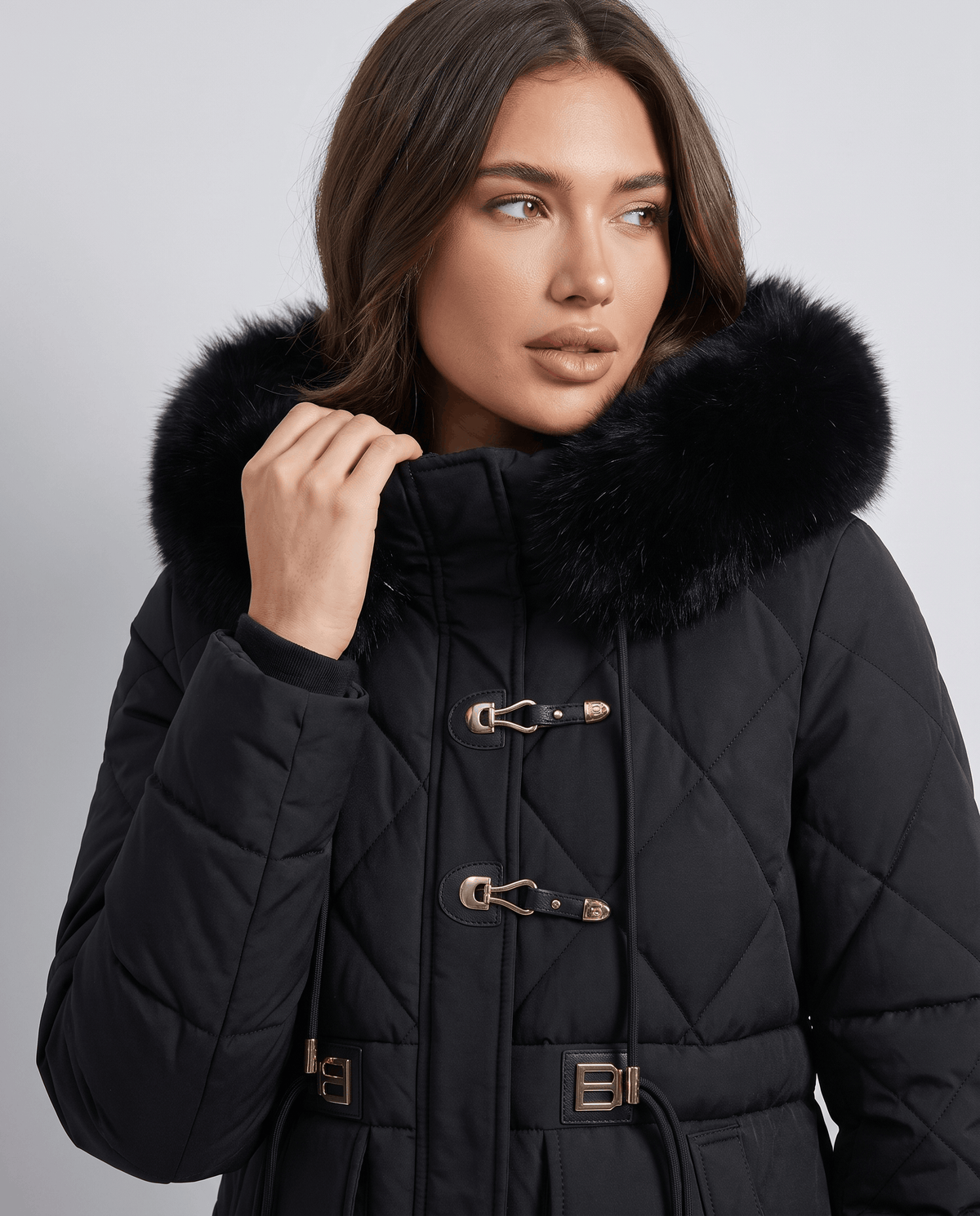 Model in black jacket with plush hood trim and metal hook clasps at the collar