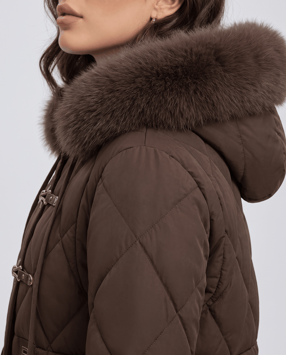 Side close-up of brown jacket hood, plush trim and diamond quilted shoulder